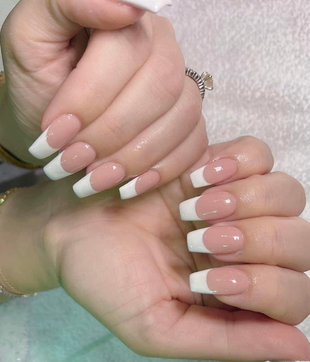 A close up of a woman 's nails with a white french manicure