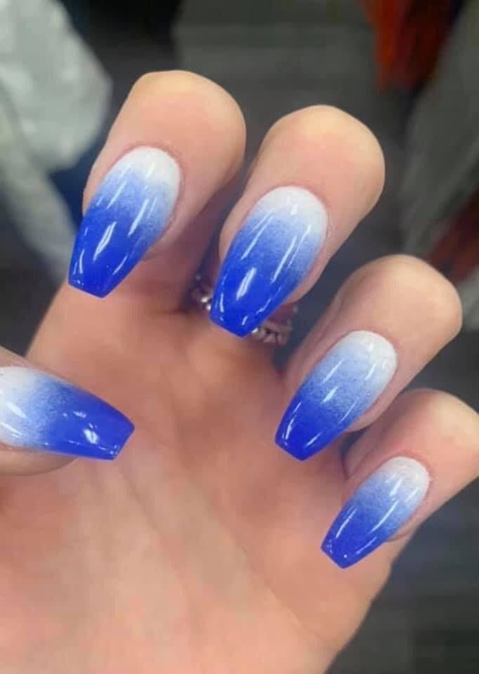 A close up of a person 's hand with blue and white ombre nails.