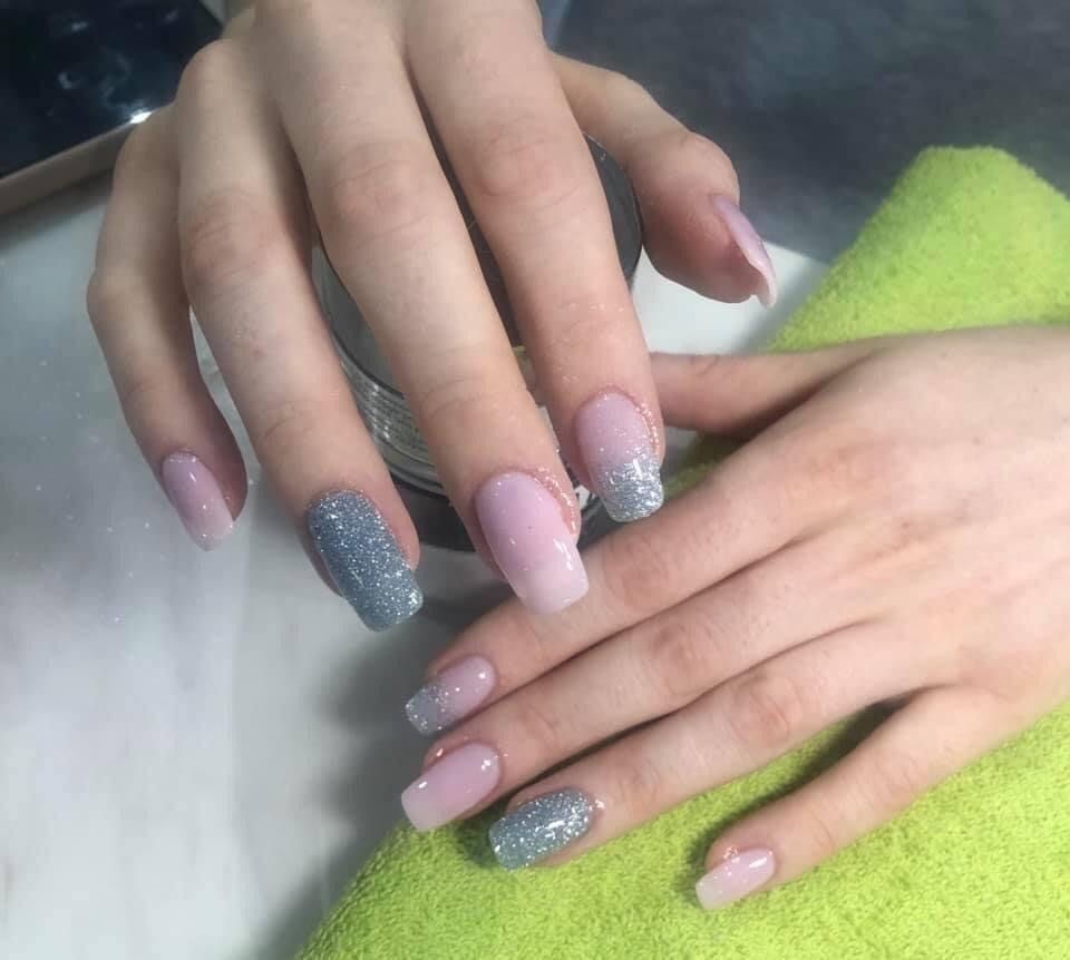 A woman 's nails are painted pink and gray and are sitting on a green towel.