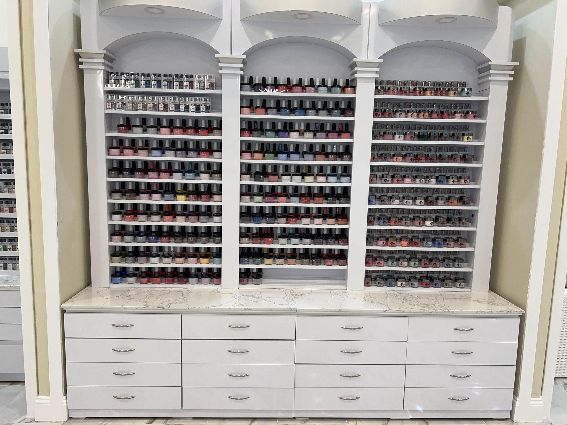 A wall filled with lots of nail polish and drawers