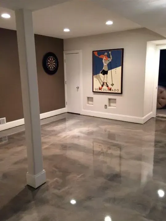 Basement with shiny metallic flooring, dartboard, ski art, and white support column.