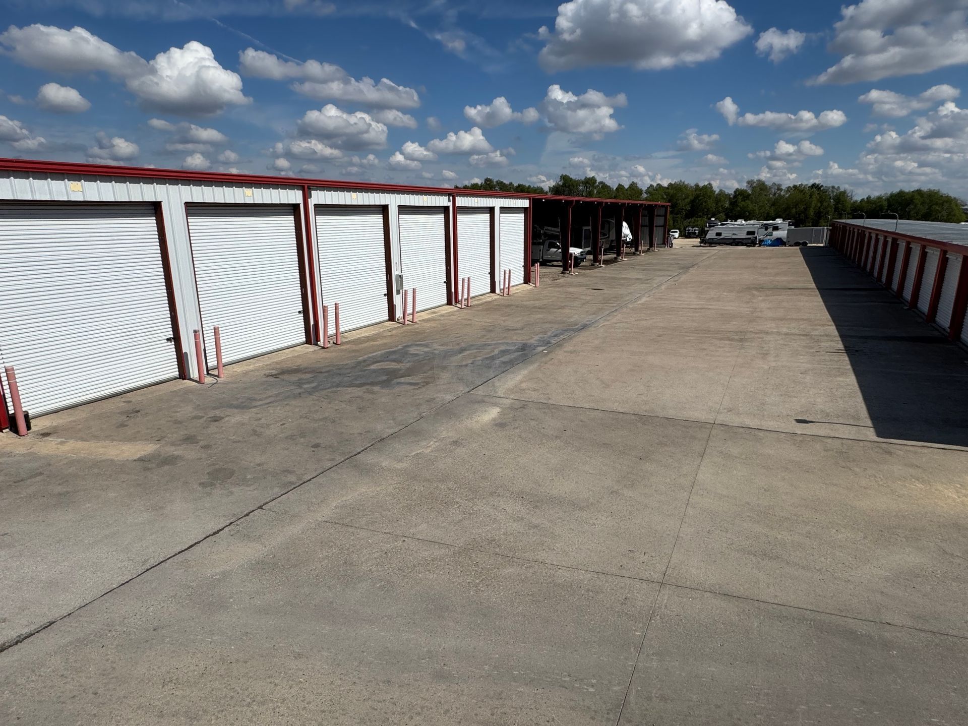 Row of white storage units with red trim under a partly cloudy blue sky.