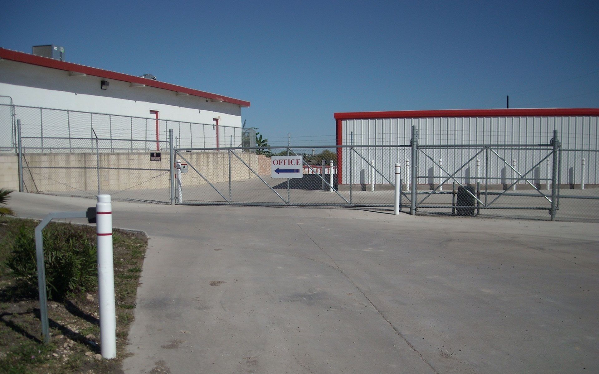 Metal gates open to an industrial building under a clear blue sky.