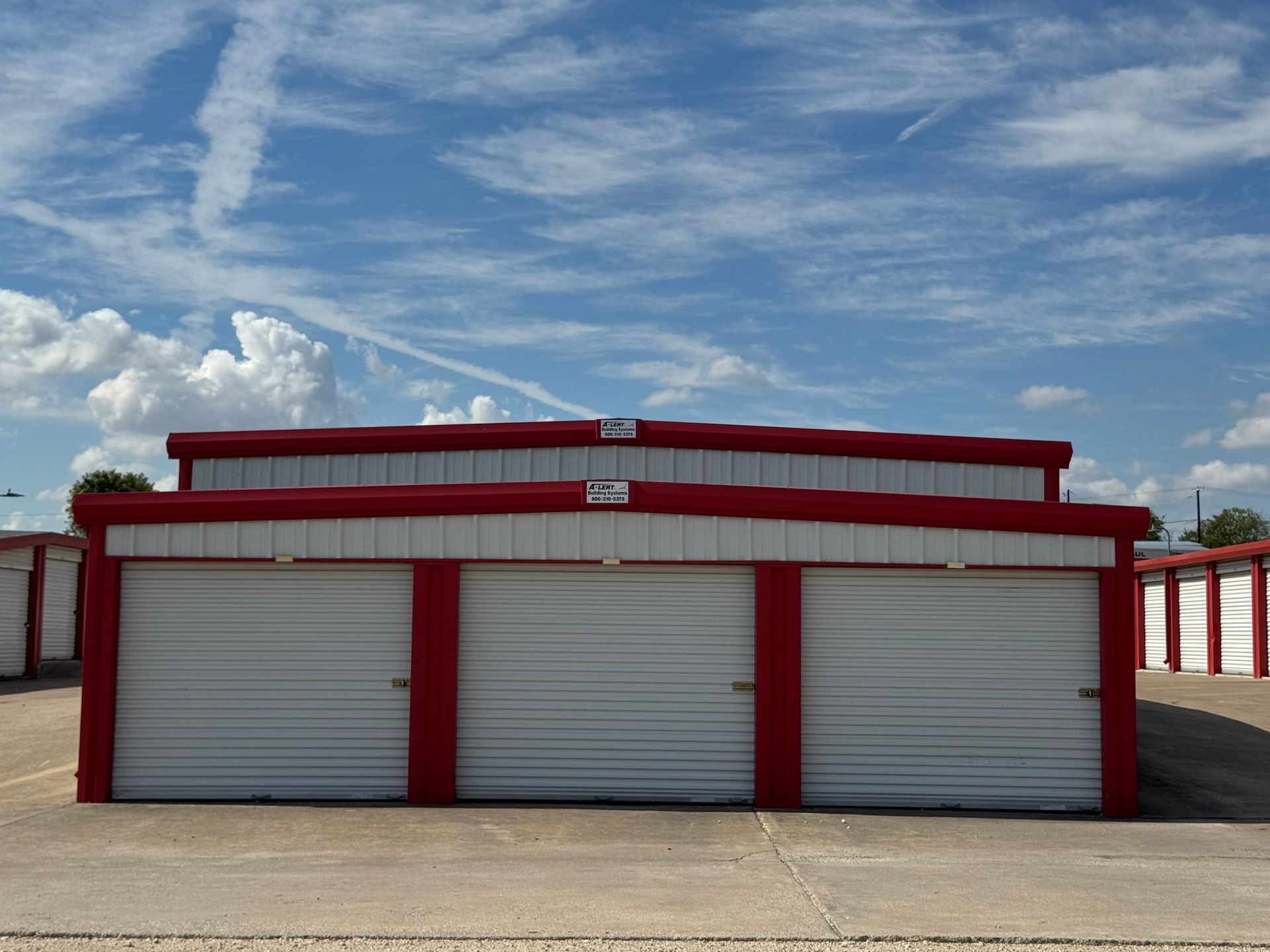 Red and white storage units under a blue sky with clouds.