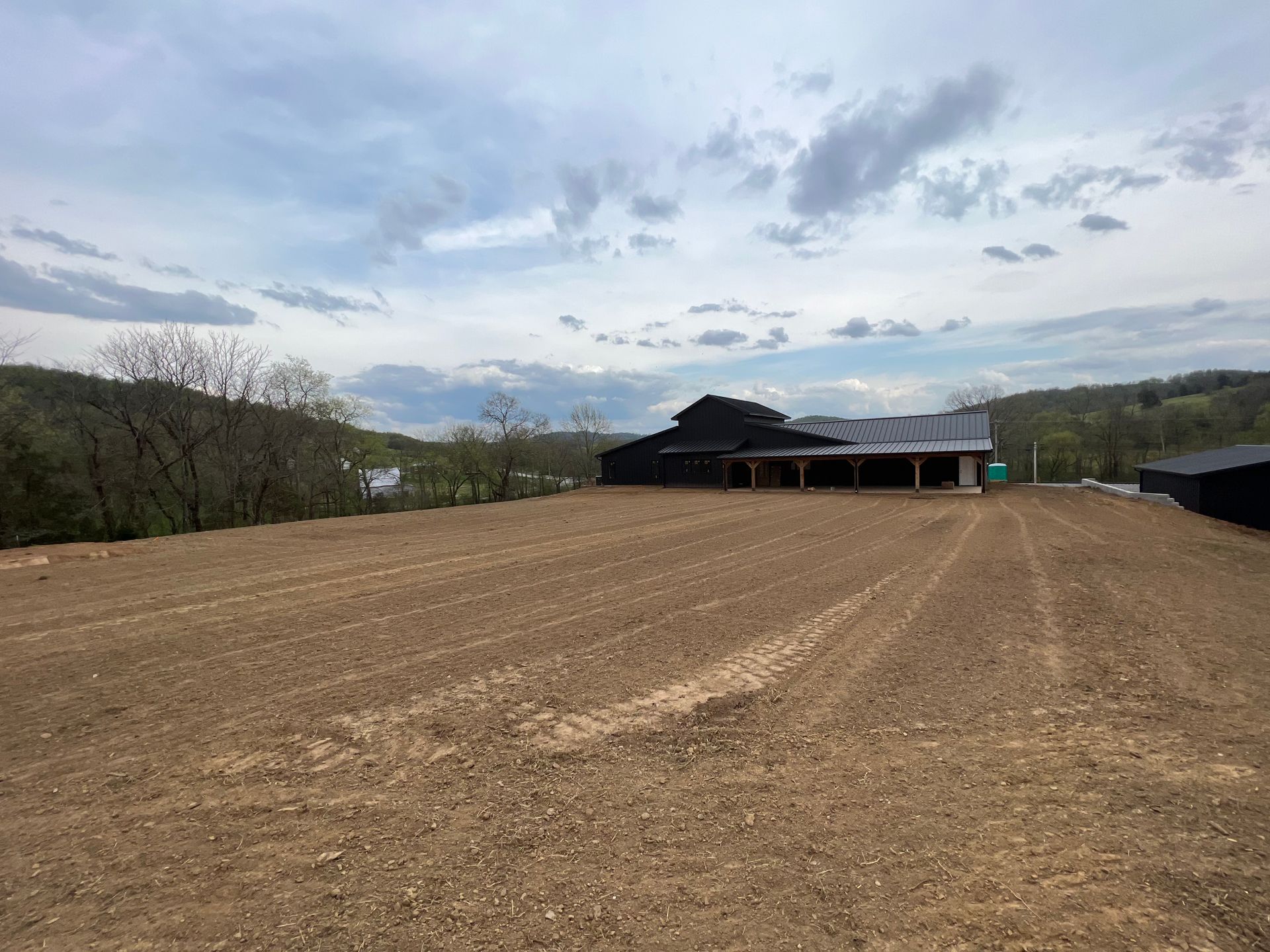 A large dirt field with a barn in the background.