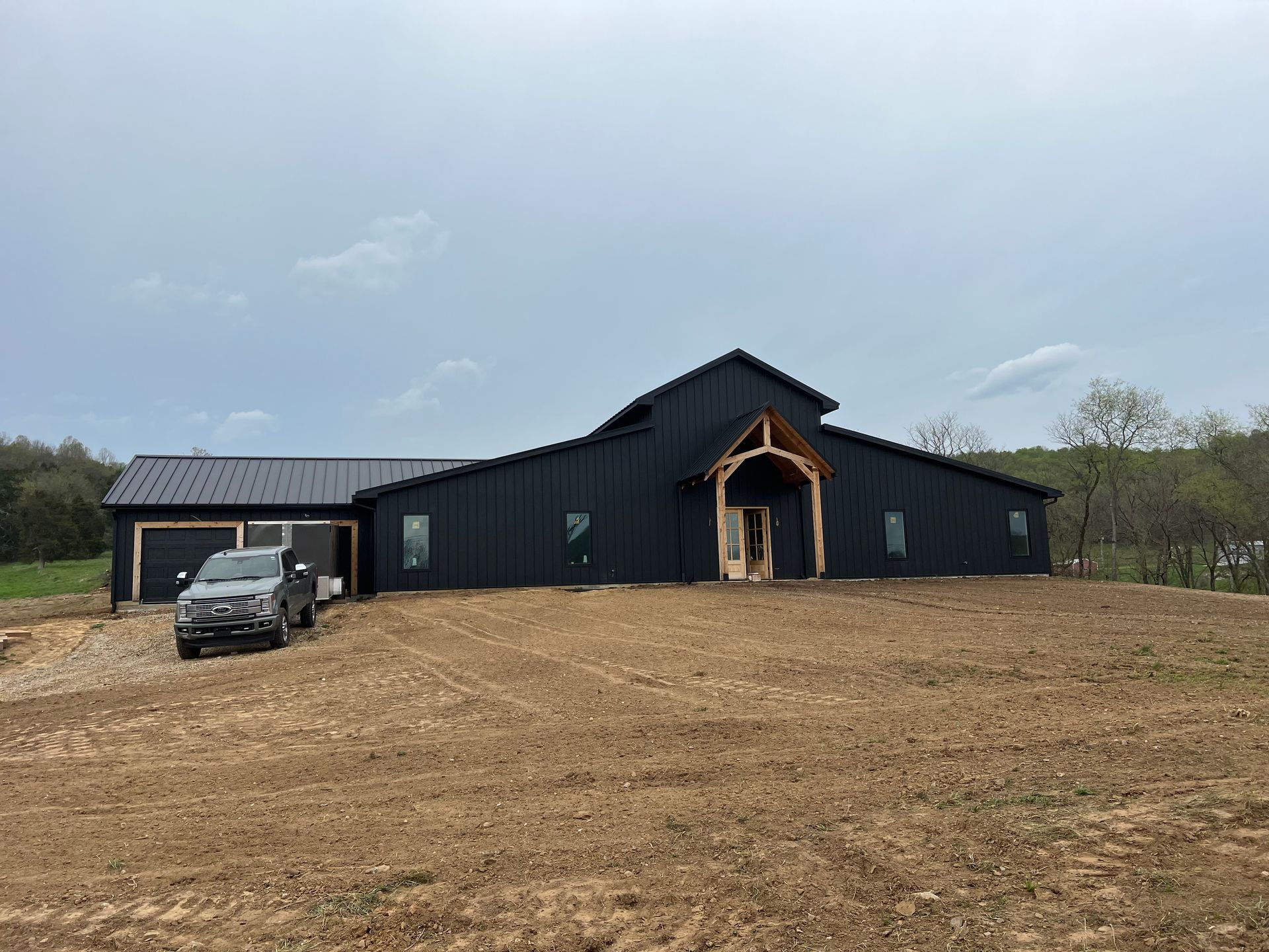 A large black barn with a car parked in front of it.