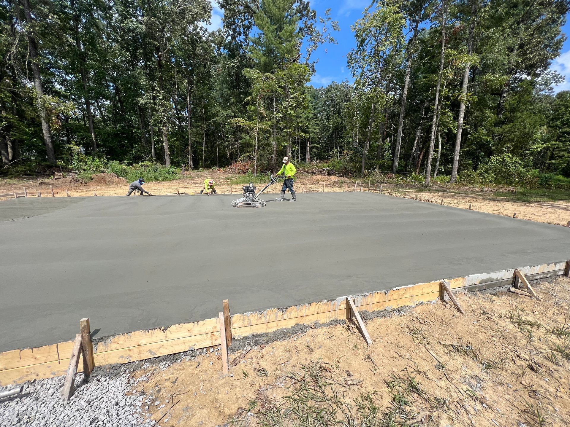 A group of construction workers are working on a concrete driveway.