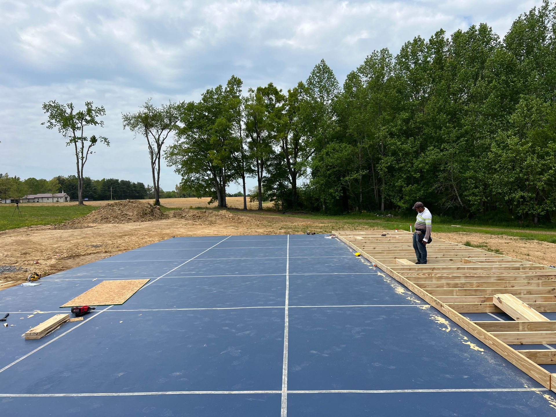 A man is standing on a blue concrete floor in a field.