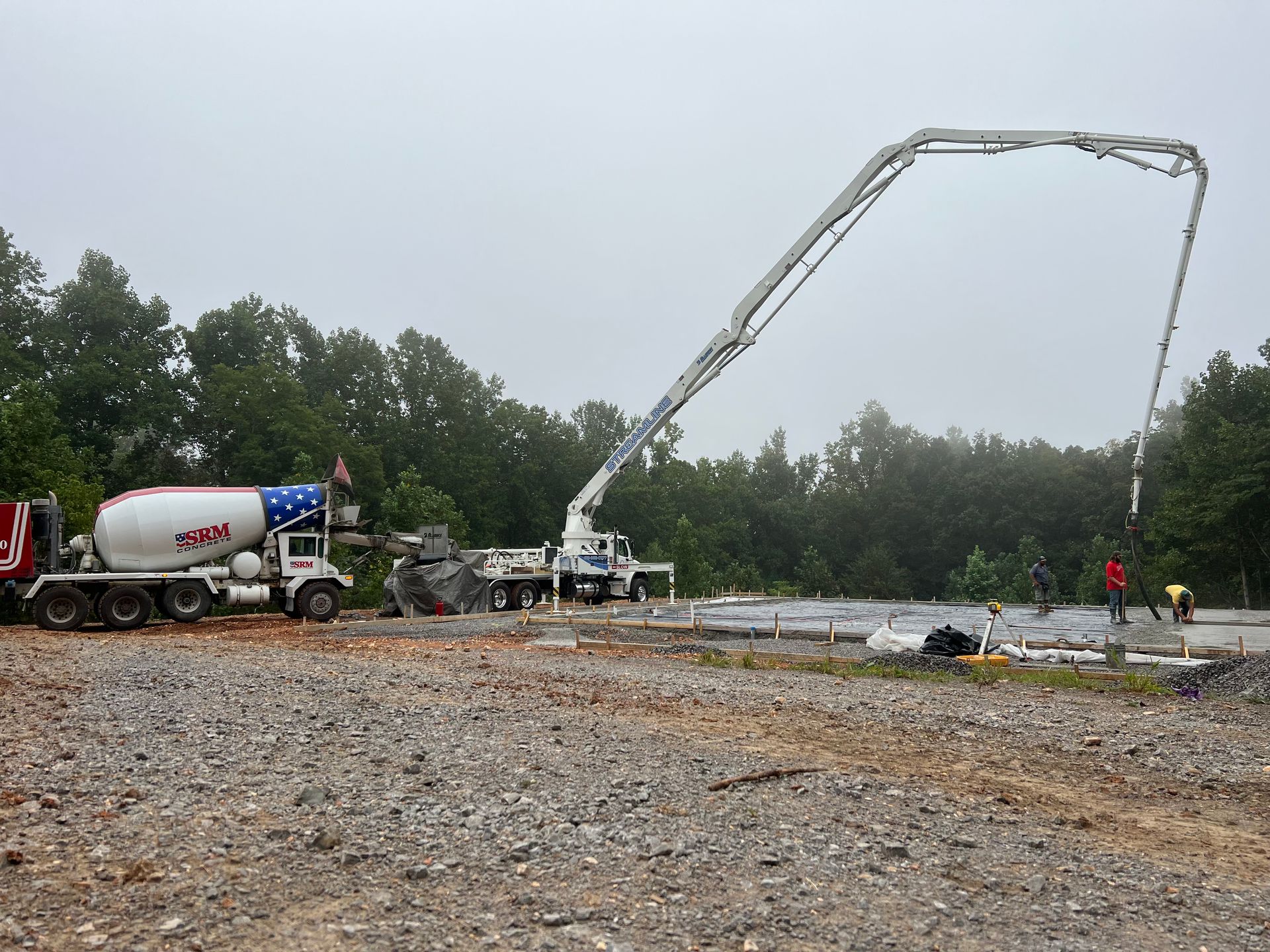 A concrete pump is being used to pour concrete on a gravel road.