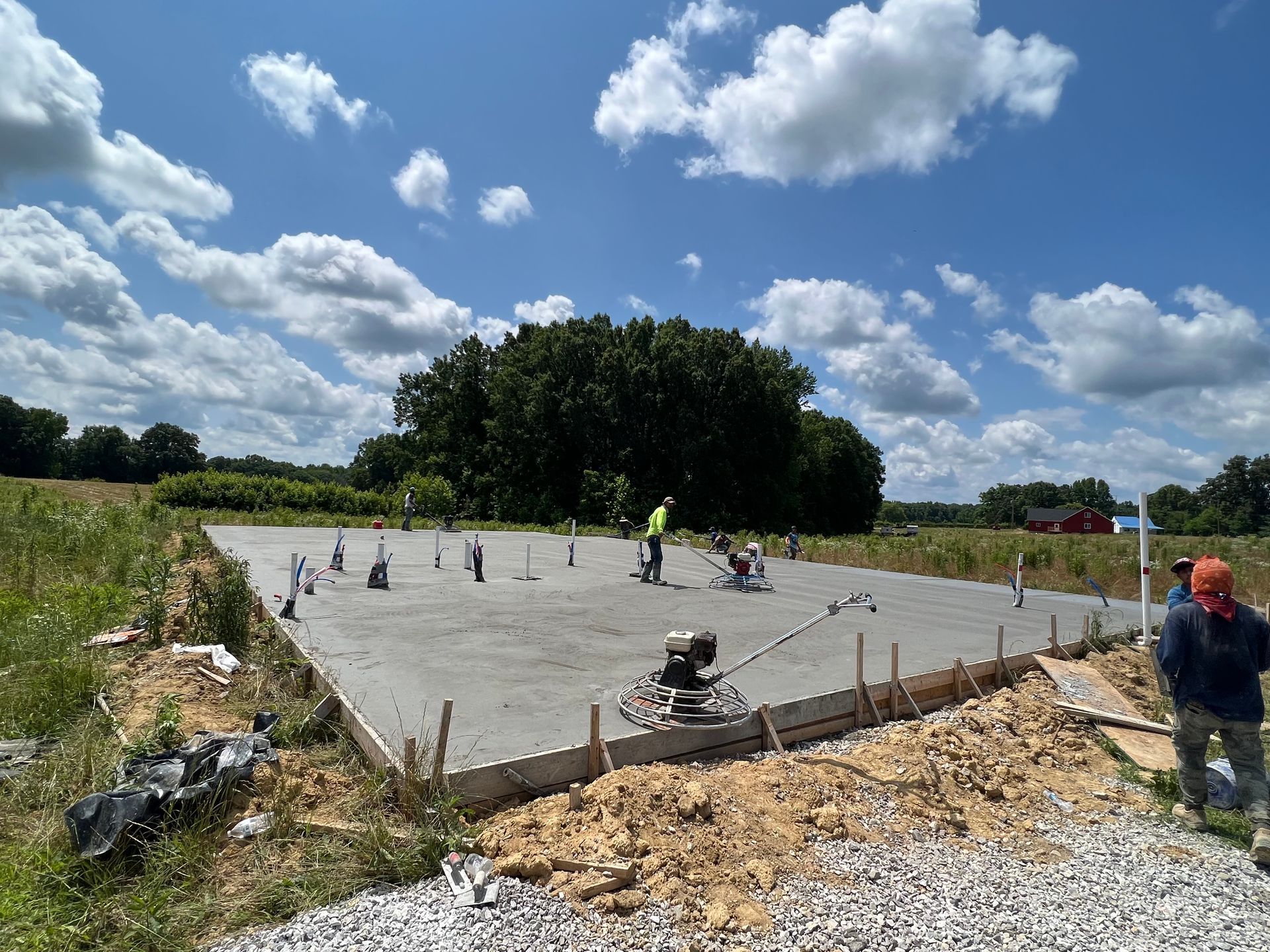 A group of construction workers are working on a concrete slab in a field.