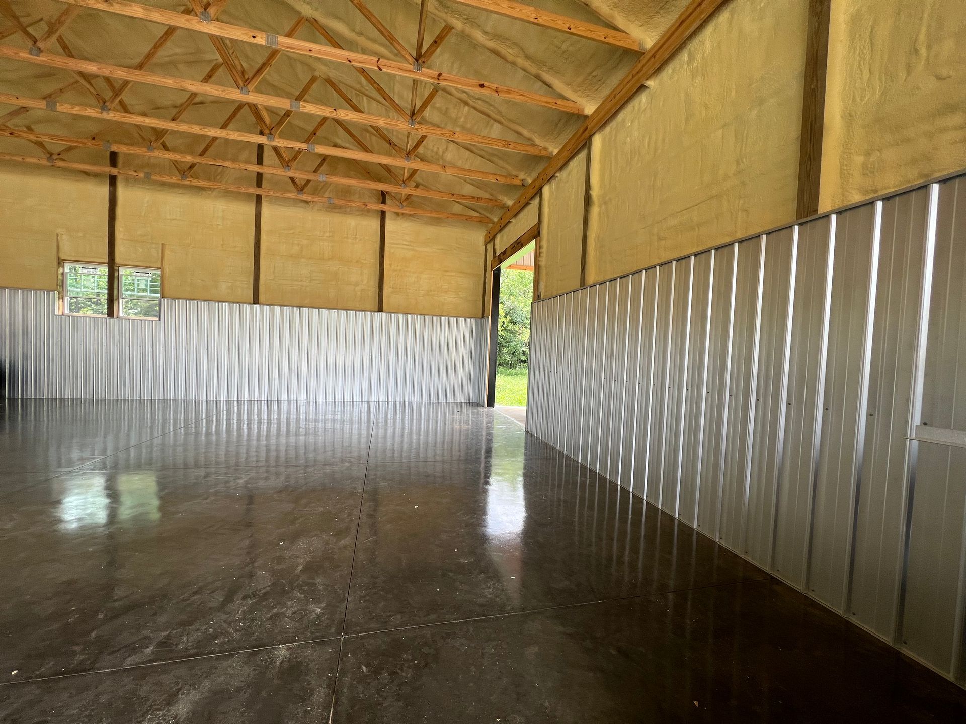 A large empty building with a concrete floor and a wooden ceiling.