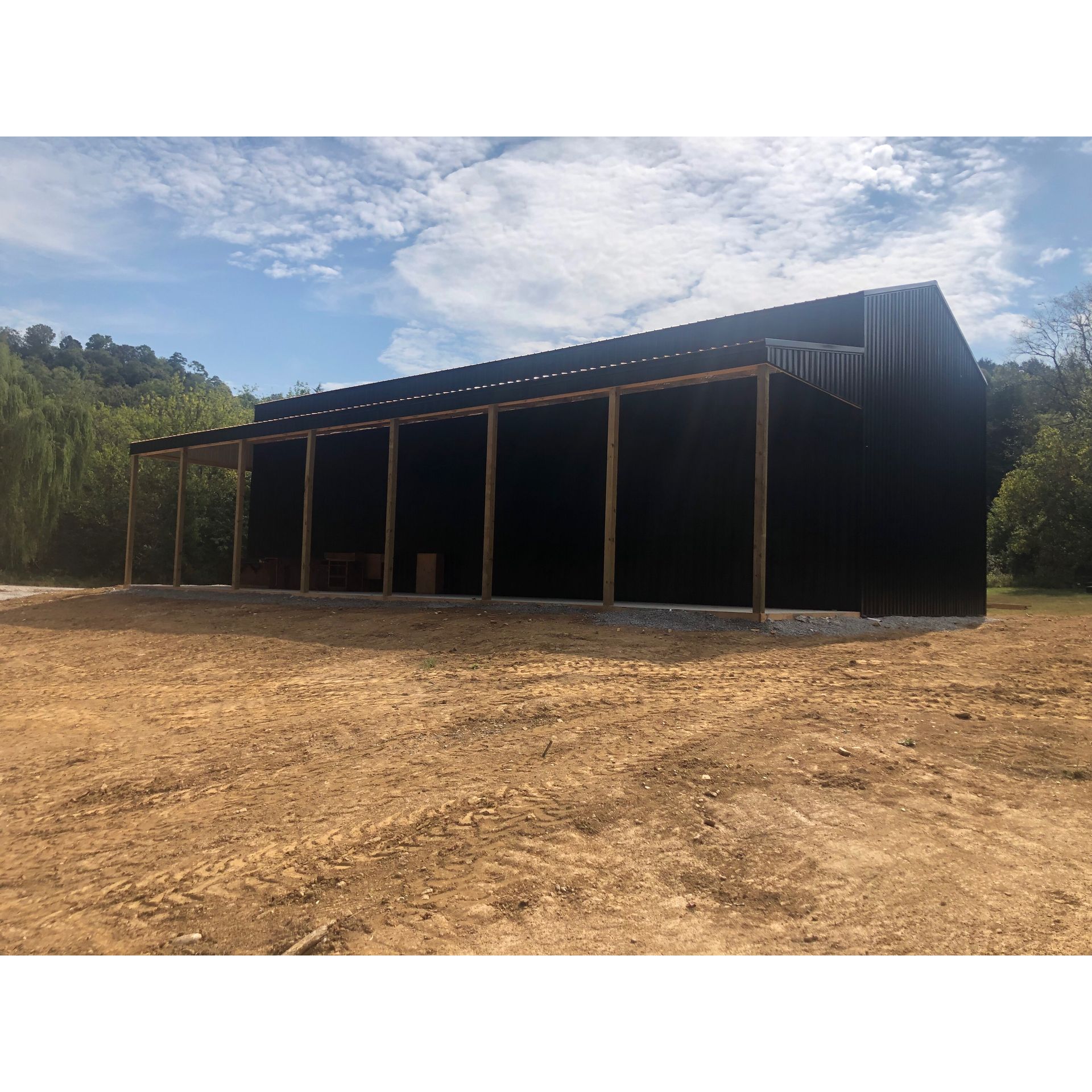 A large black building is sitting in the middle of a dirt field.