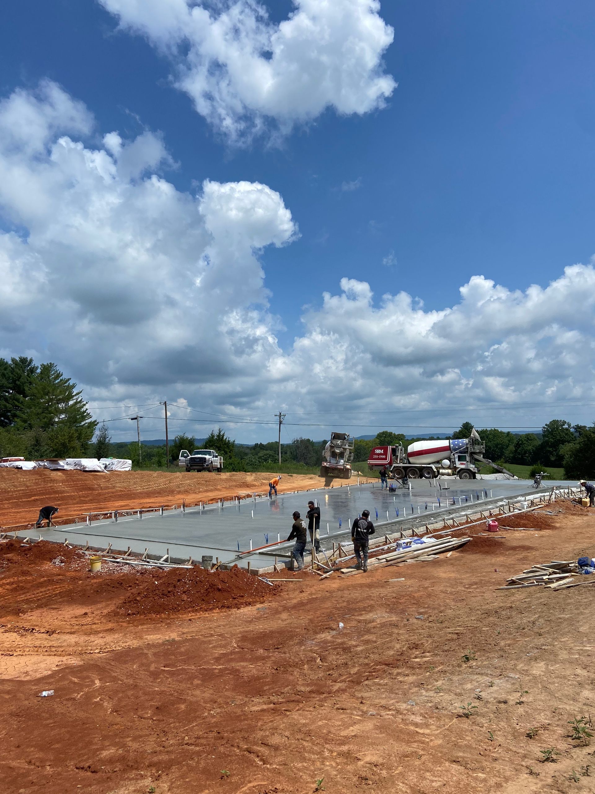 A large concrete slab is being poured on a dirt field.