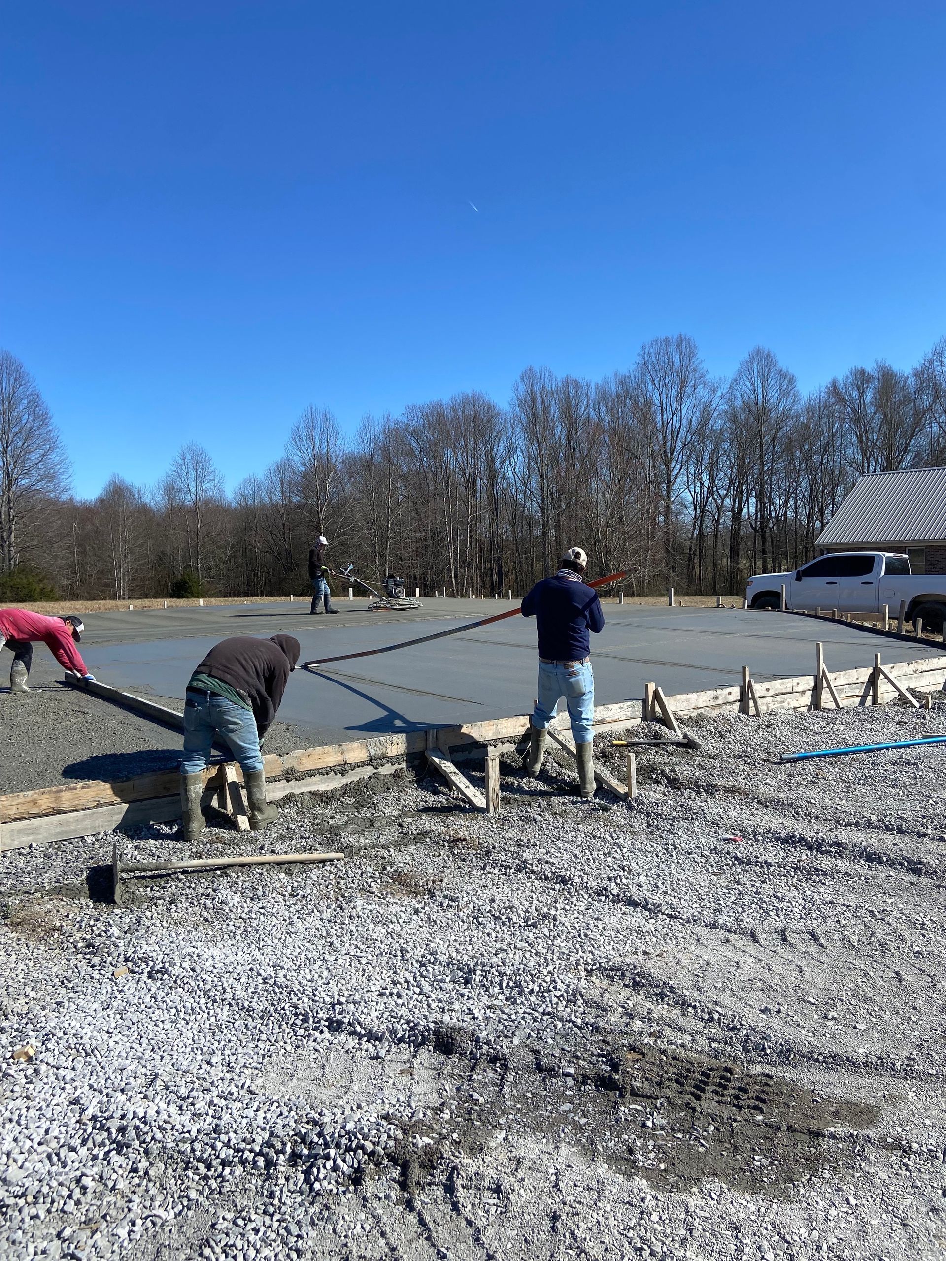 A group of construction workers are working on a concrete driveway.