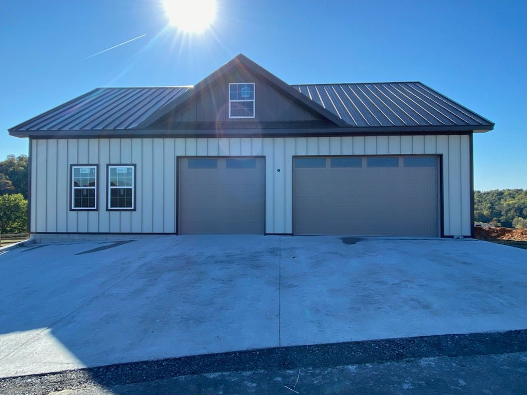 A large house with two garage doors and a black roof
