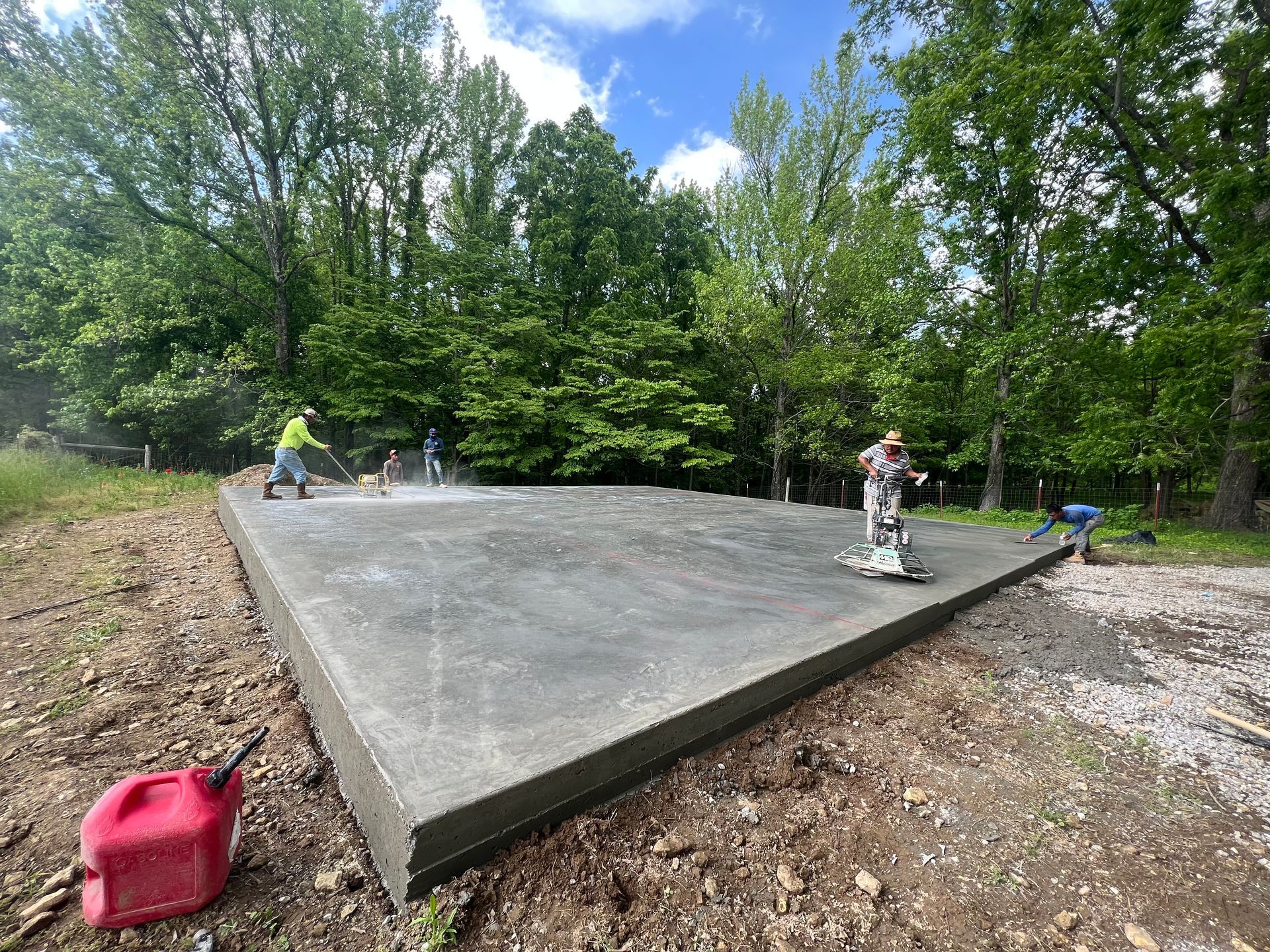 A concrete slab is being built in a field with trees in the background.