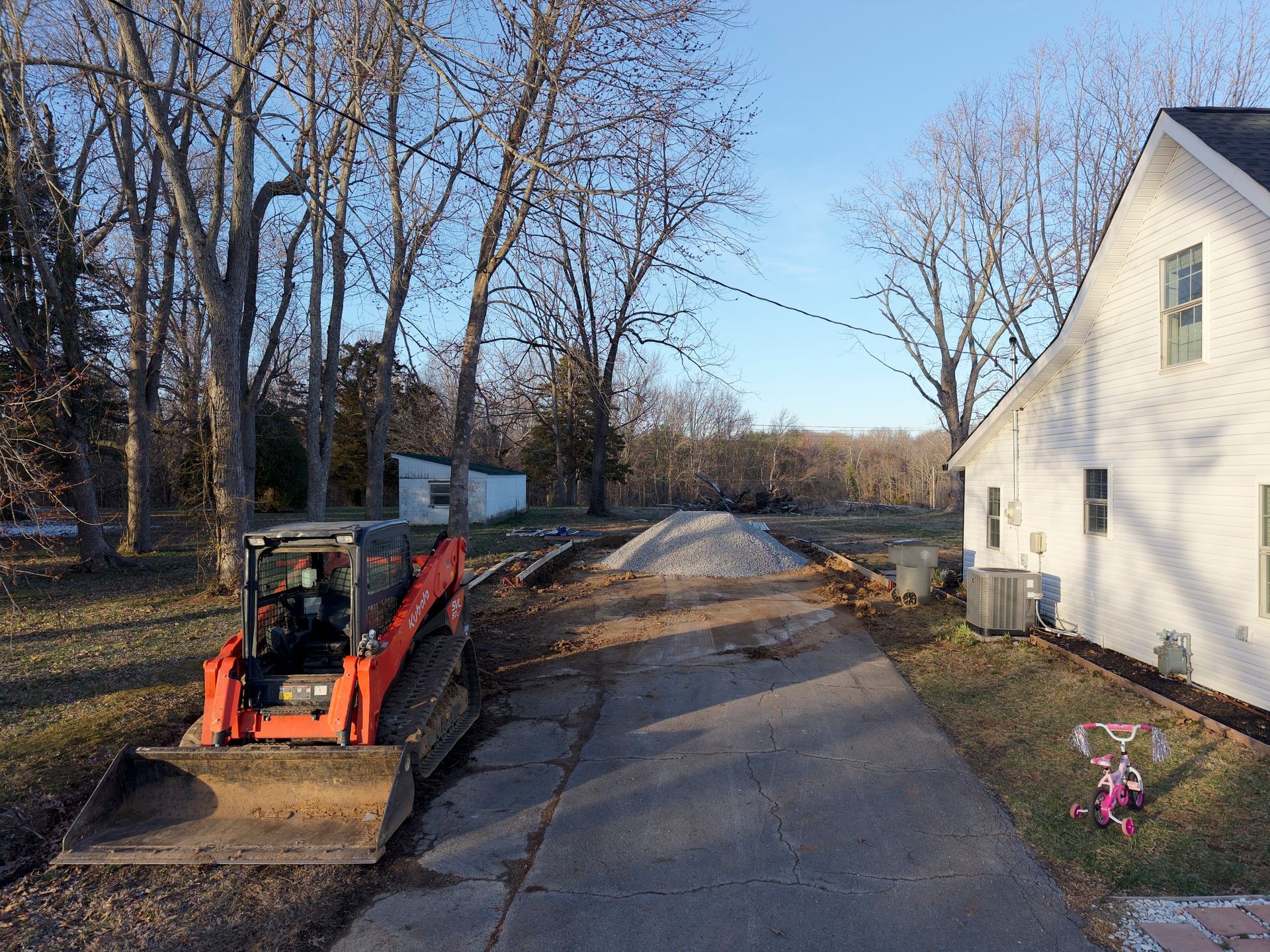 A bulldozer is parked on the side of a road next to a house.