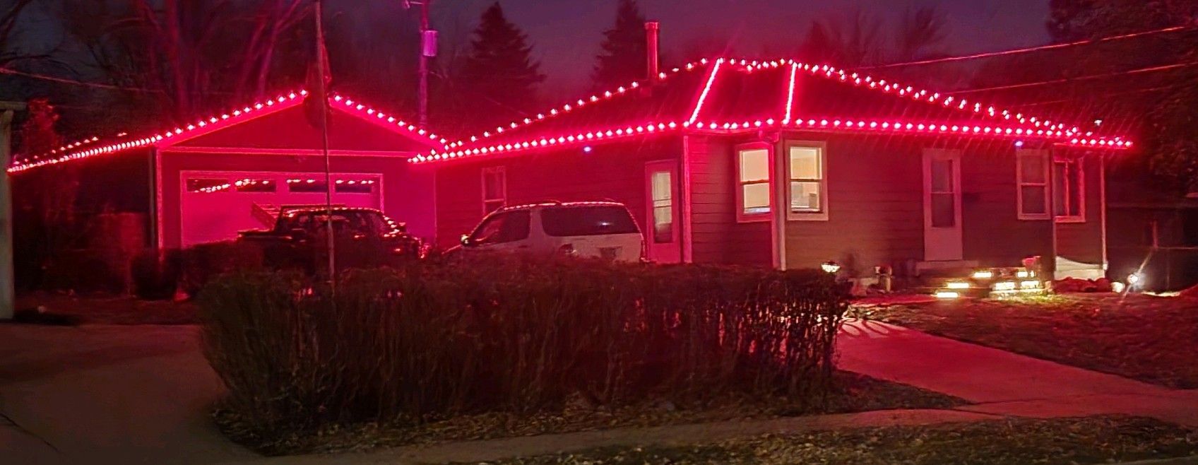 A house is decorated with red christmas lights at night.