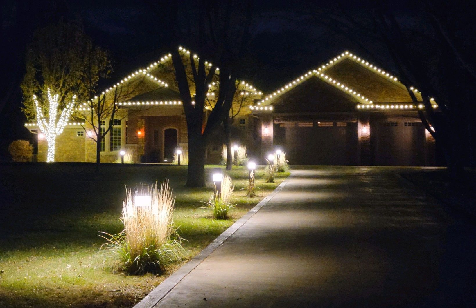 A house with christmas lights on it is lit up at night.