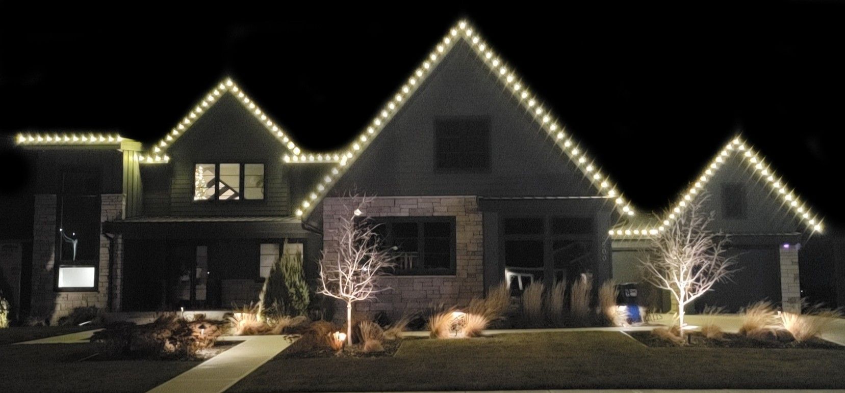 A large house is lit up at night with christmas lights on the roof