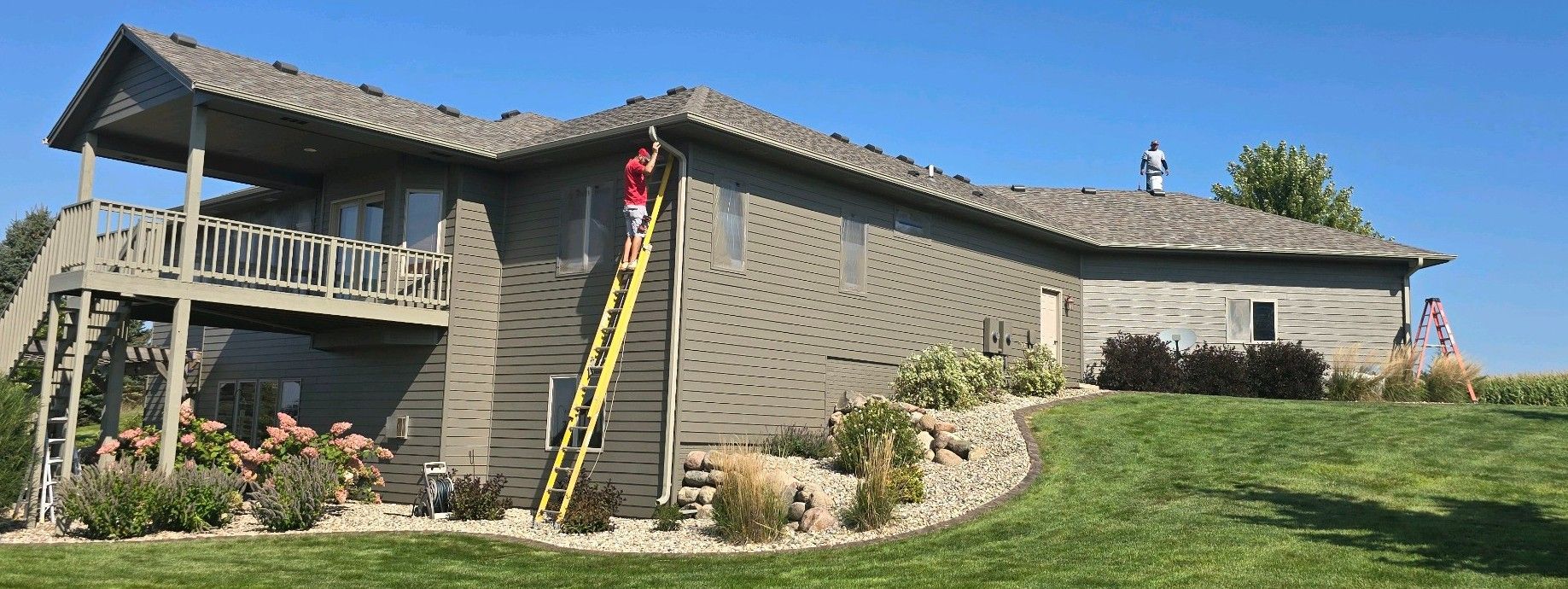 A man is standing on a ladder on the side of a house.