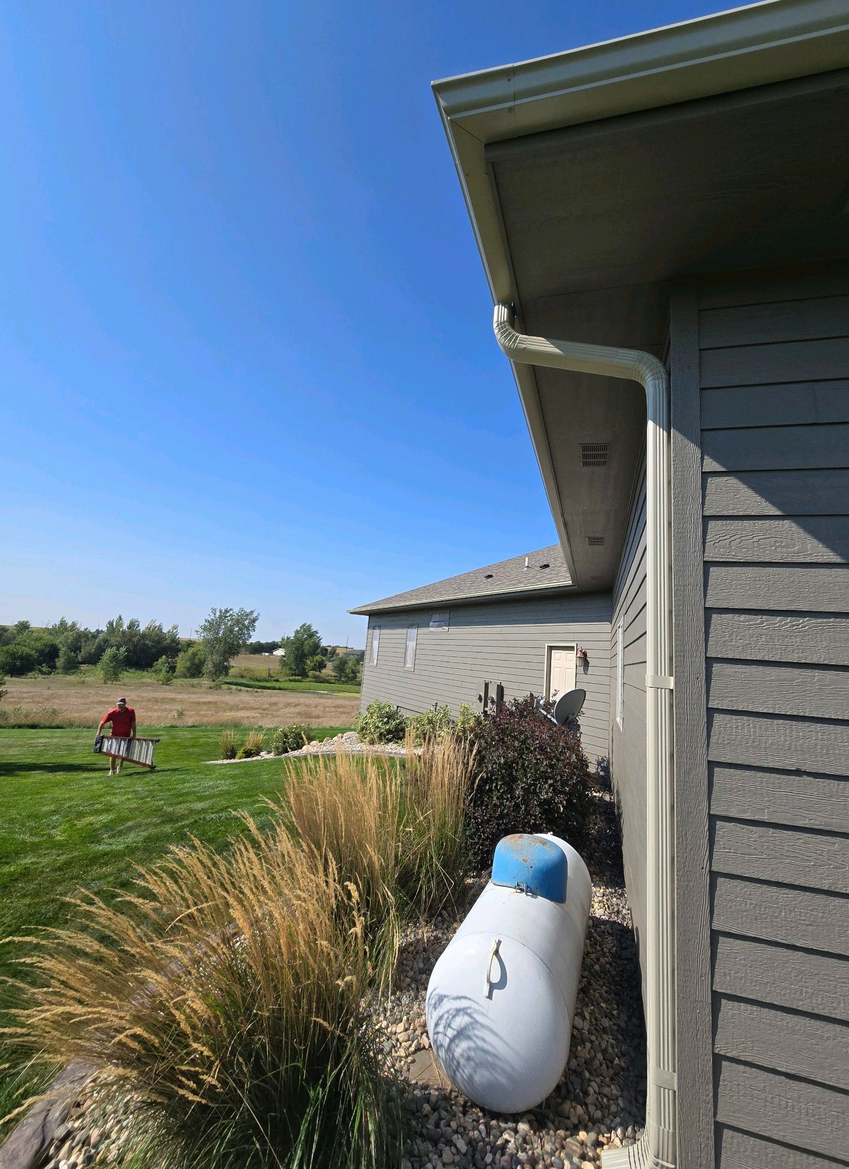 A man is standing in the grass in front of a house.