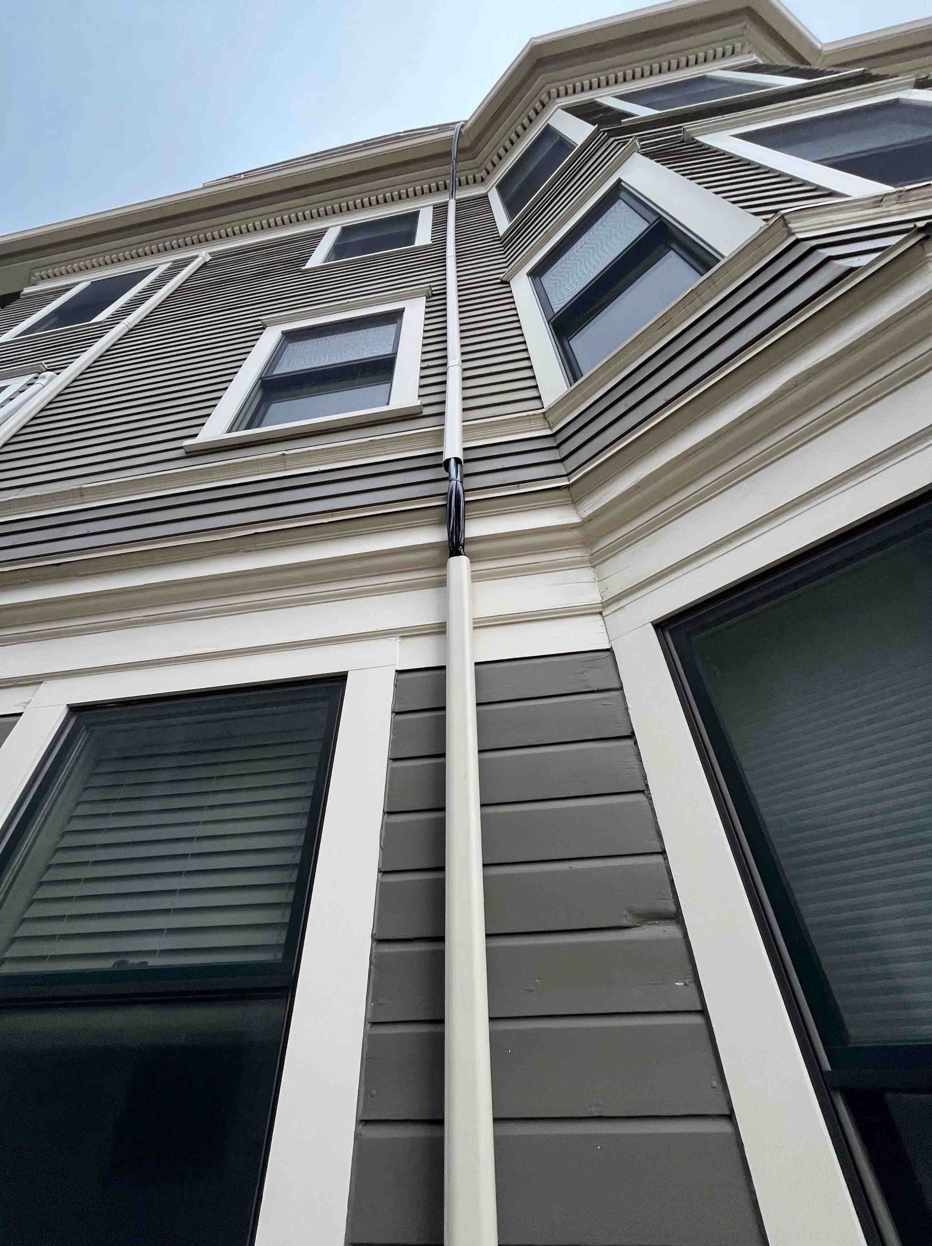 Exterior of a Victorian-style building with bay windows, gray siding, white trim, and a downspout.