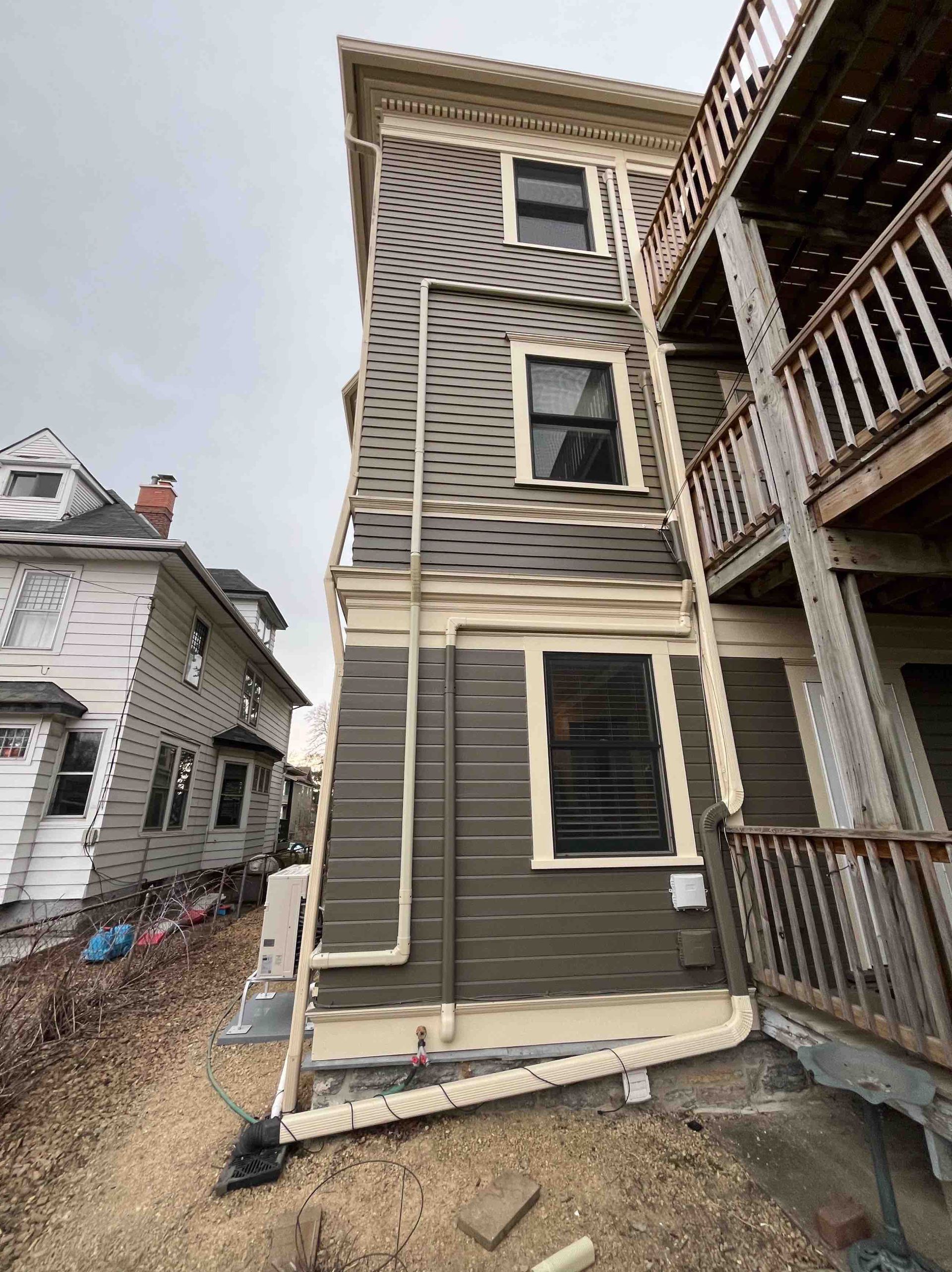 Gray multi-story building with a wooden porch on the right side under an overcast sky.
