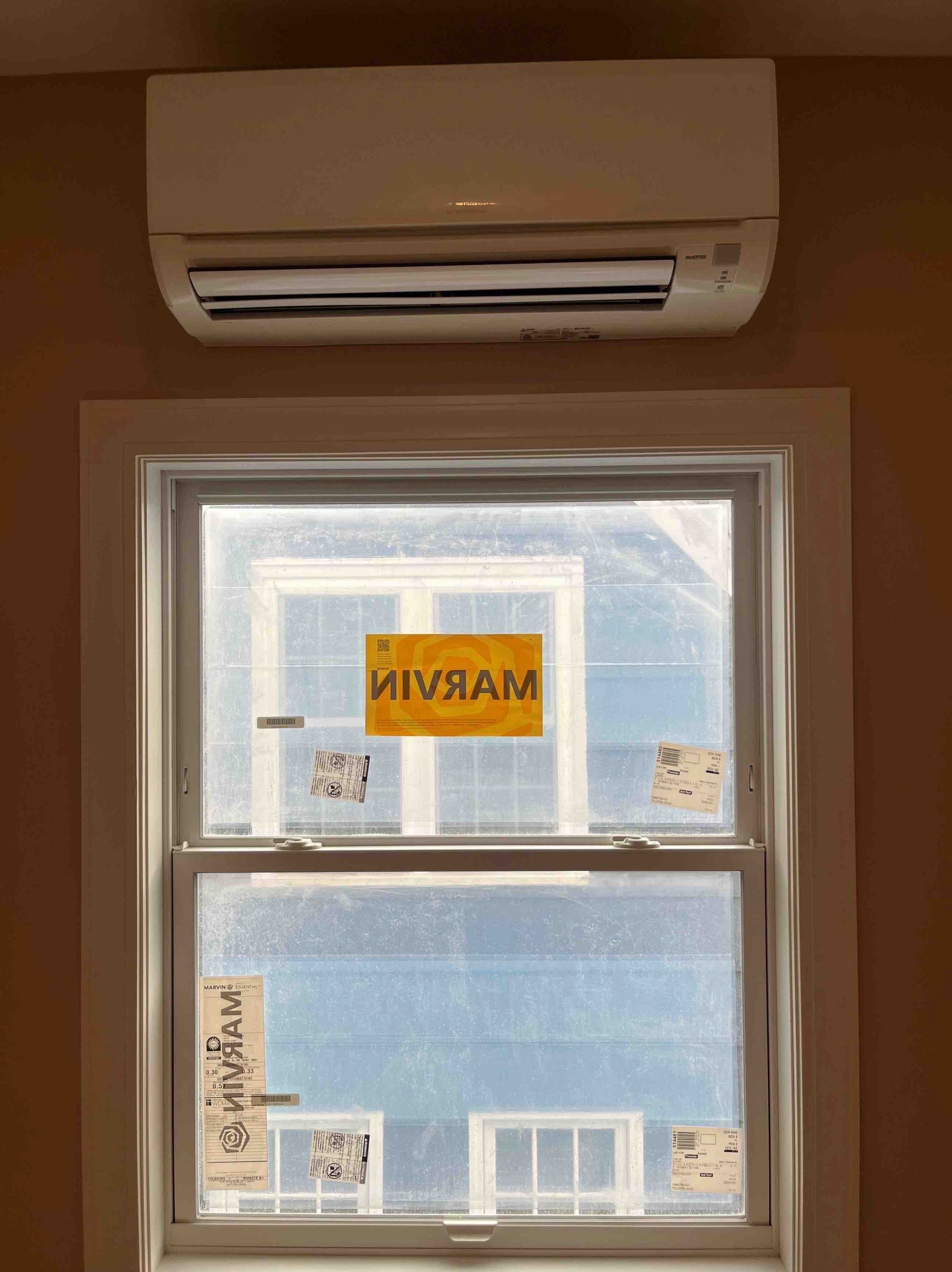 Air conditioning unit above a window, interior shot. Window is covered.