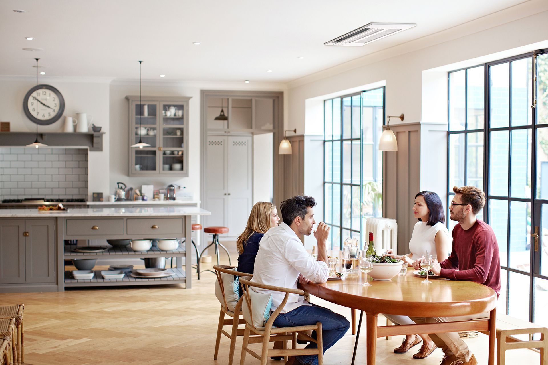 People at a table in a well-lit dining room. Kitchen in background.