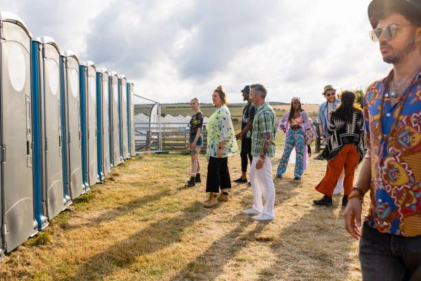 A group of people are standing in front of a row of portable toilets.