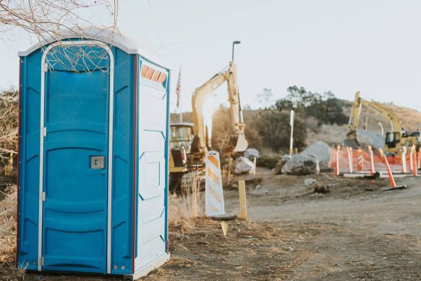 A blue portable toilet is sitting in the middle of a construction site.