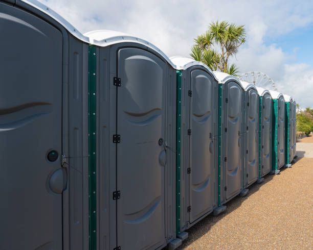 A row of portable toilets are lined up in a parking lot.
