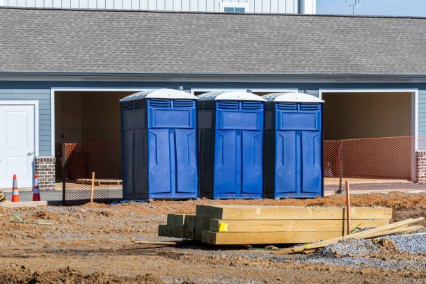 A row of blue portable toilets are sitting in front of a building under construction.