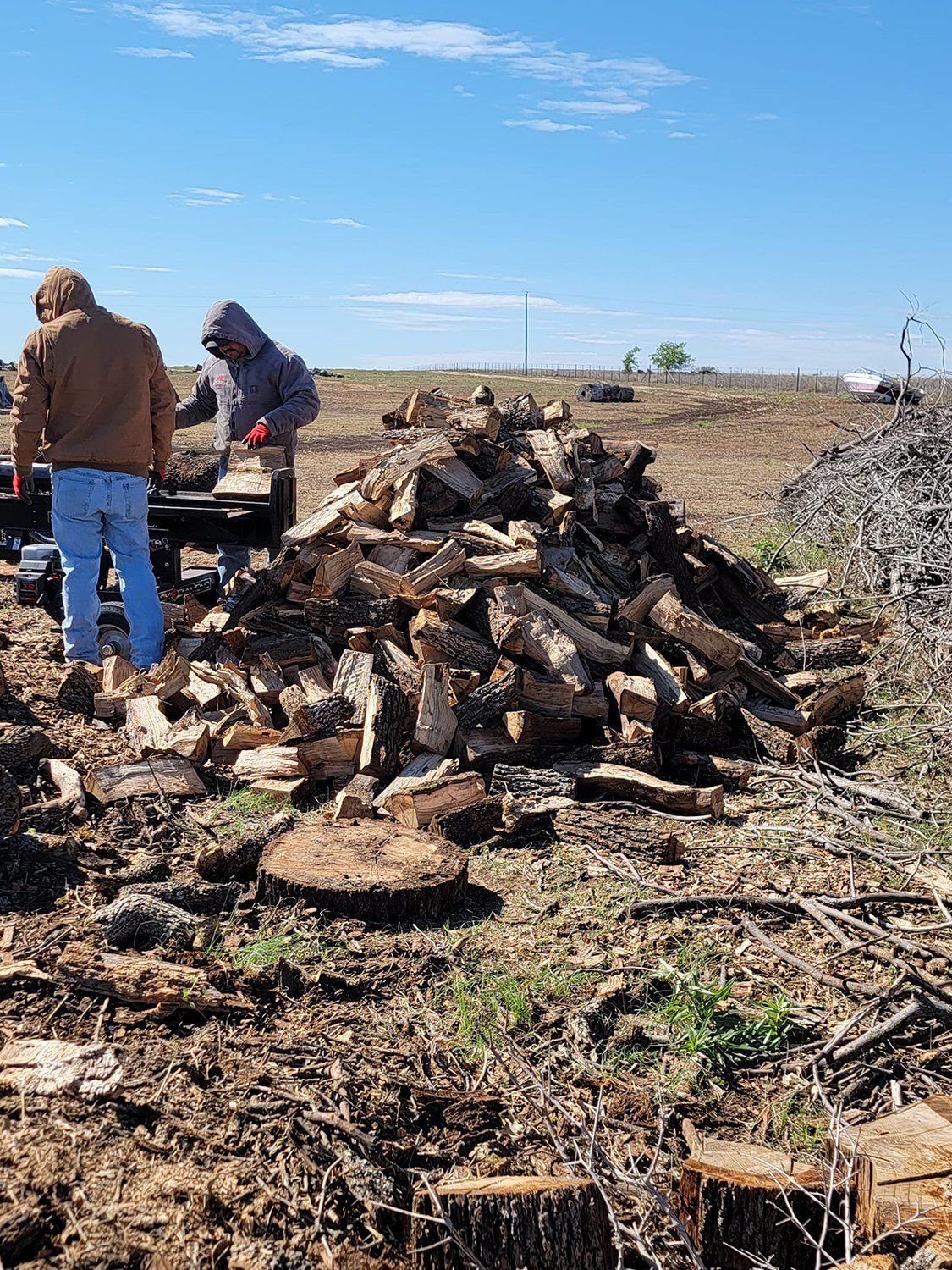 Two guys piling up firewood