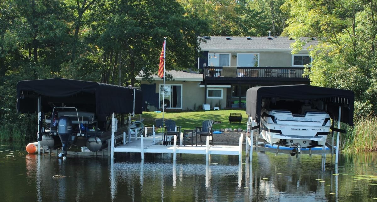 Two boats are docked at a dock in front of a house.