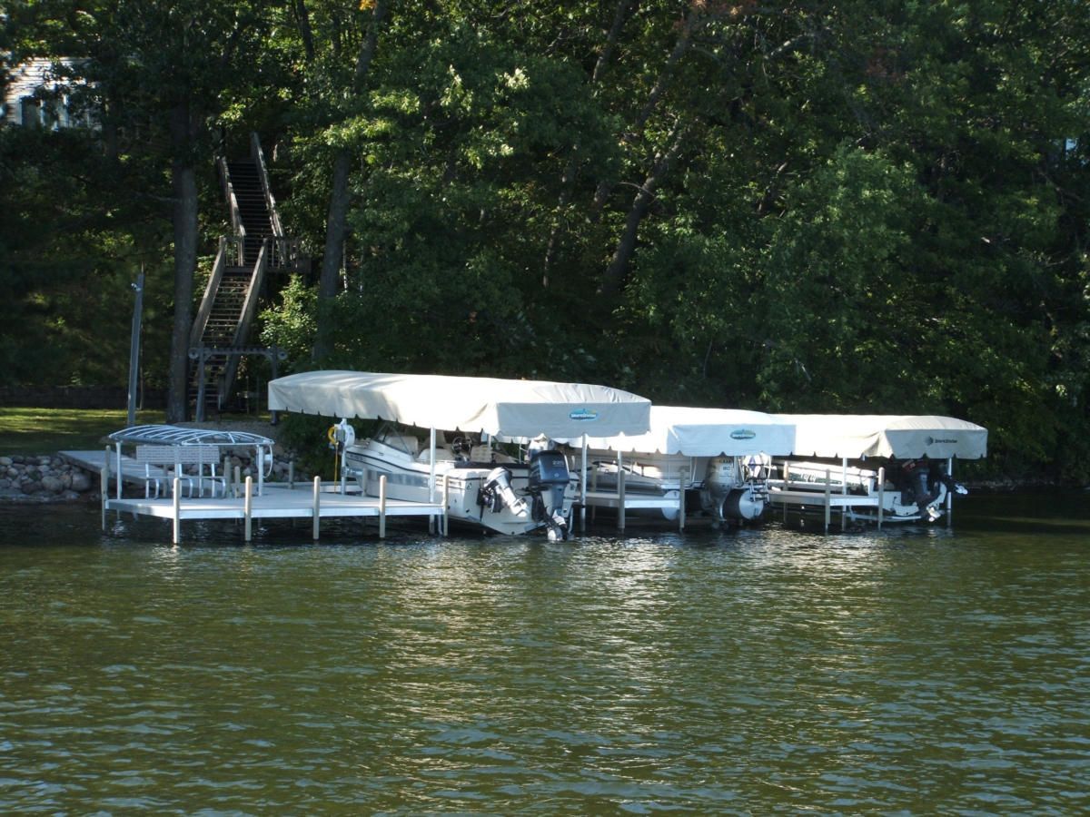 Several boats are docked at a dock on a lake