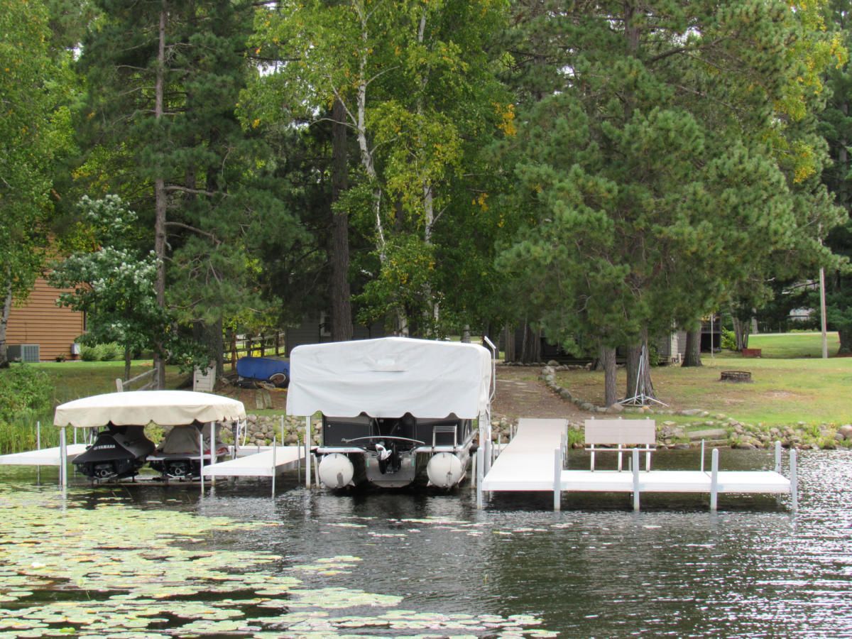 A pontoon boat is docked at a dock on a lake