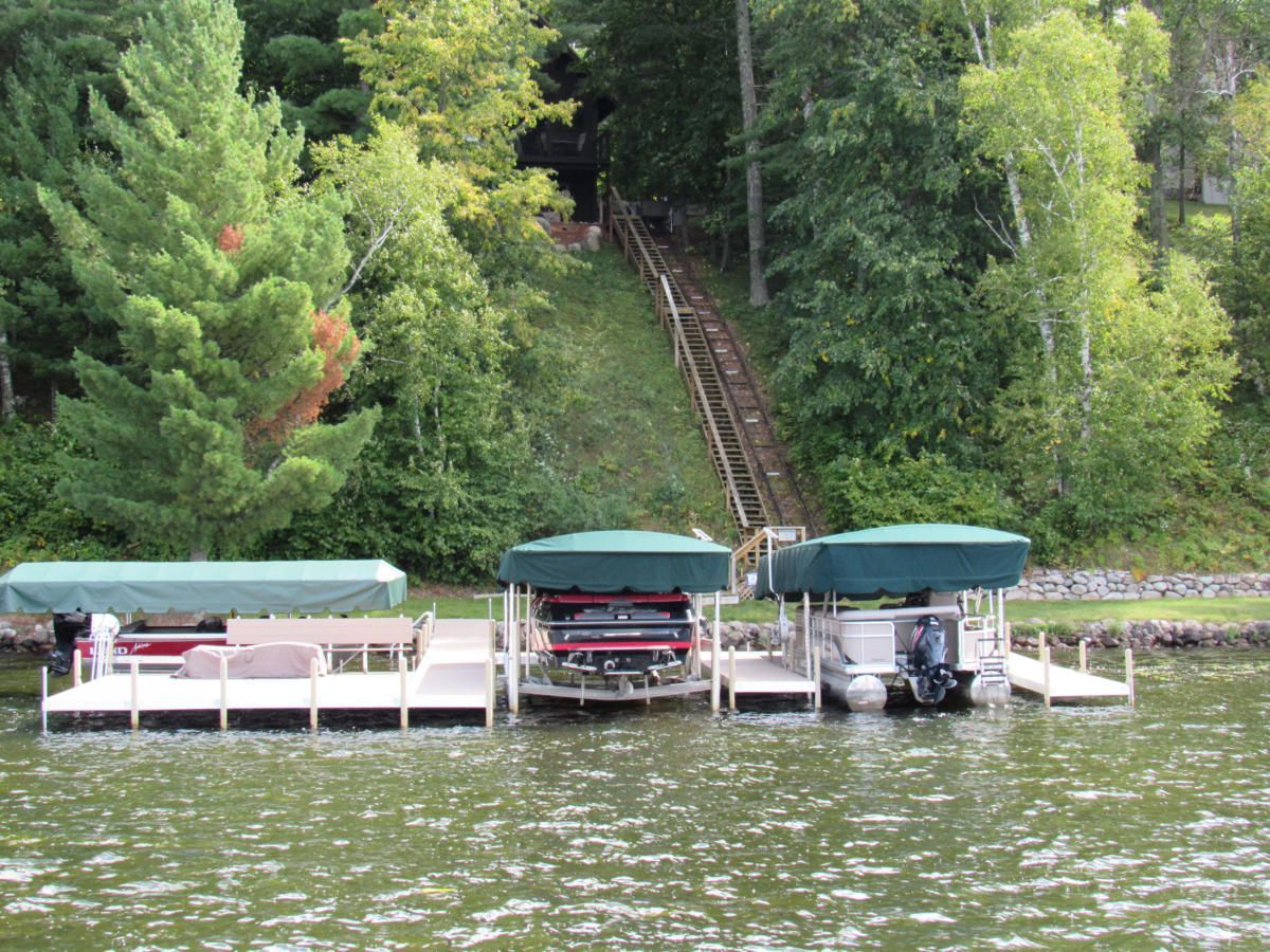 Three boats are docked at a dock on a lake.