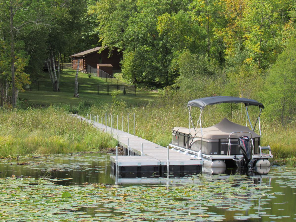 A pontoon boat is docked at a dock on a lake.