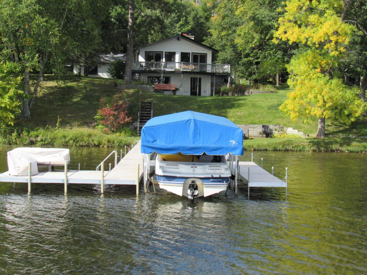 A boat is docked at a dock with a house in the background