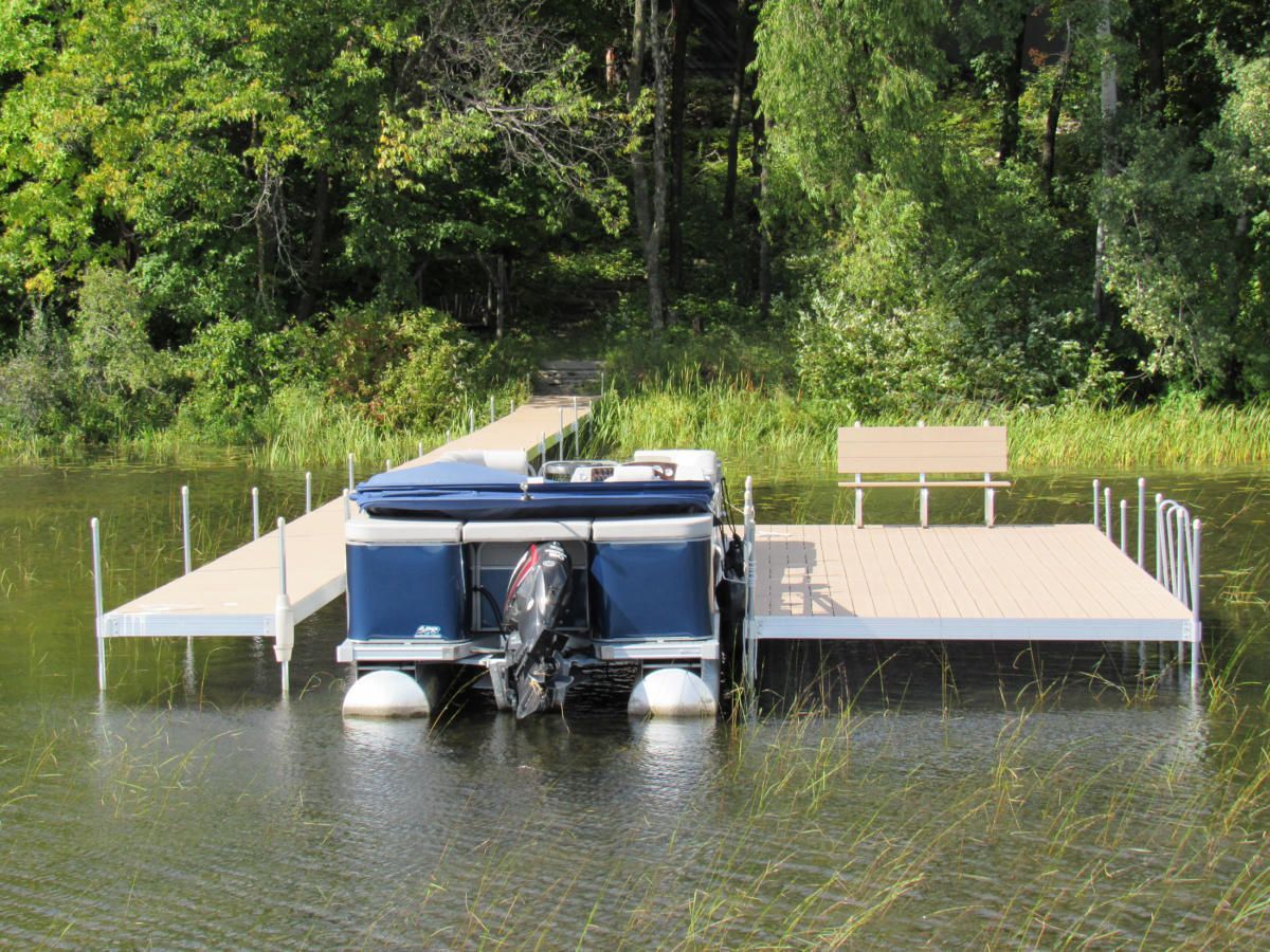 A pontoon boat is docked at a dock on a lake