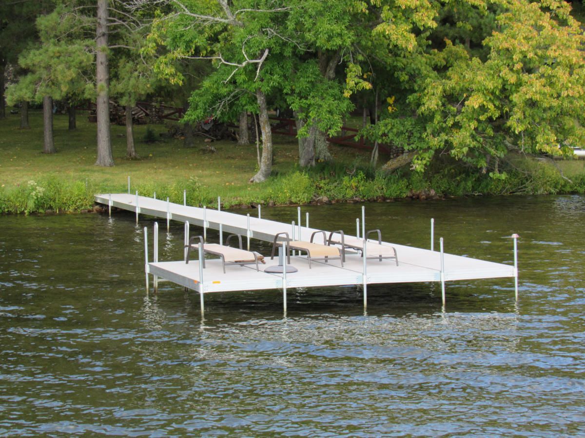 A dock with chairs on it is in the middle of a lake.