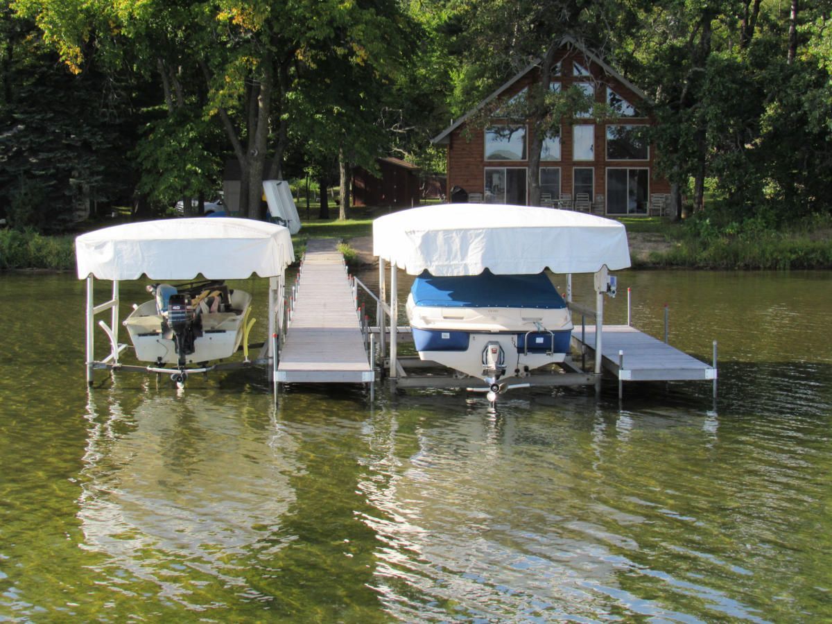 Two boats are docked at a dock with a house in the background