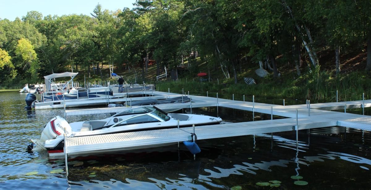 A row of boats are docked at a dock on a lake.