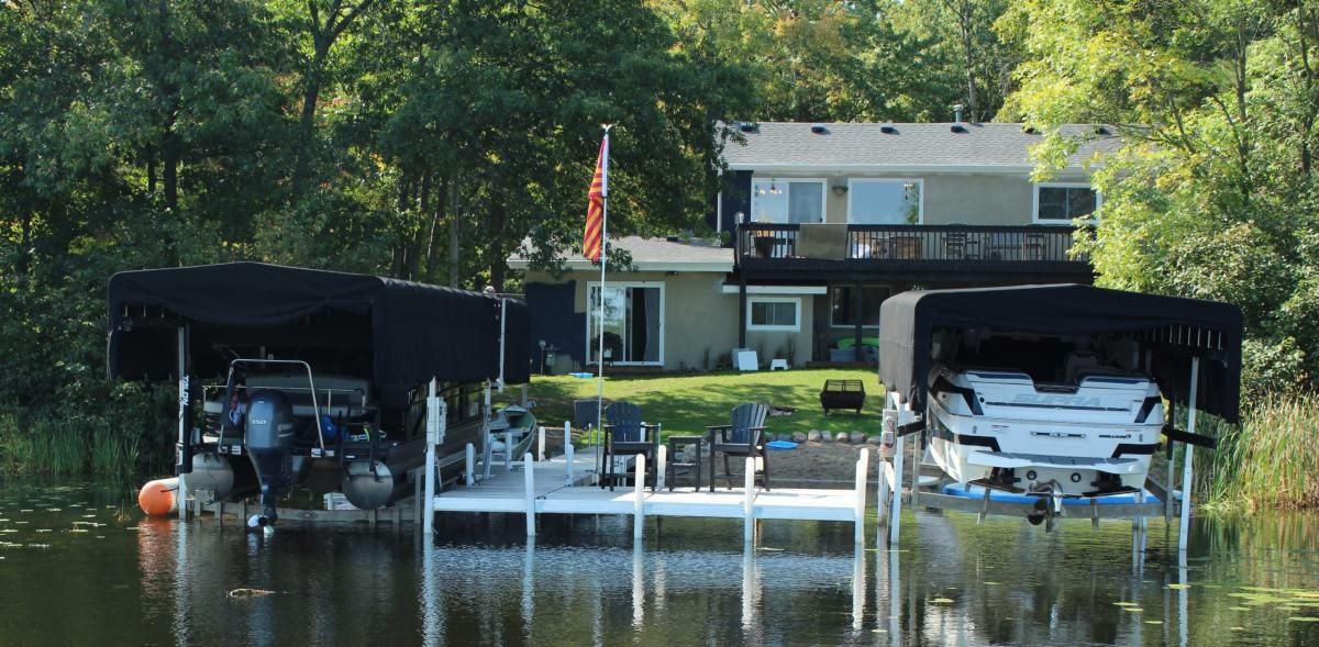 A boat is docked in front of a house on a lake.