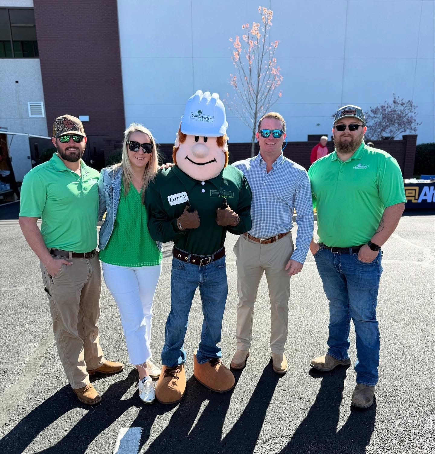 A group of people posing with a mascot in front of a building