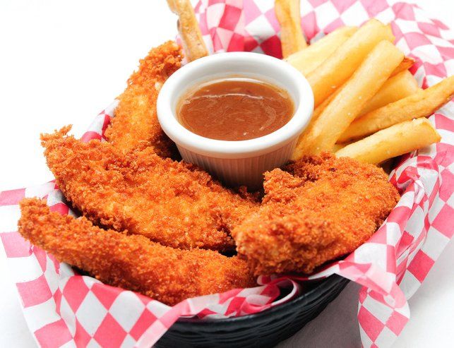 A basket of fried chicken and french fries with a dipping sauce