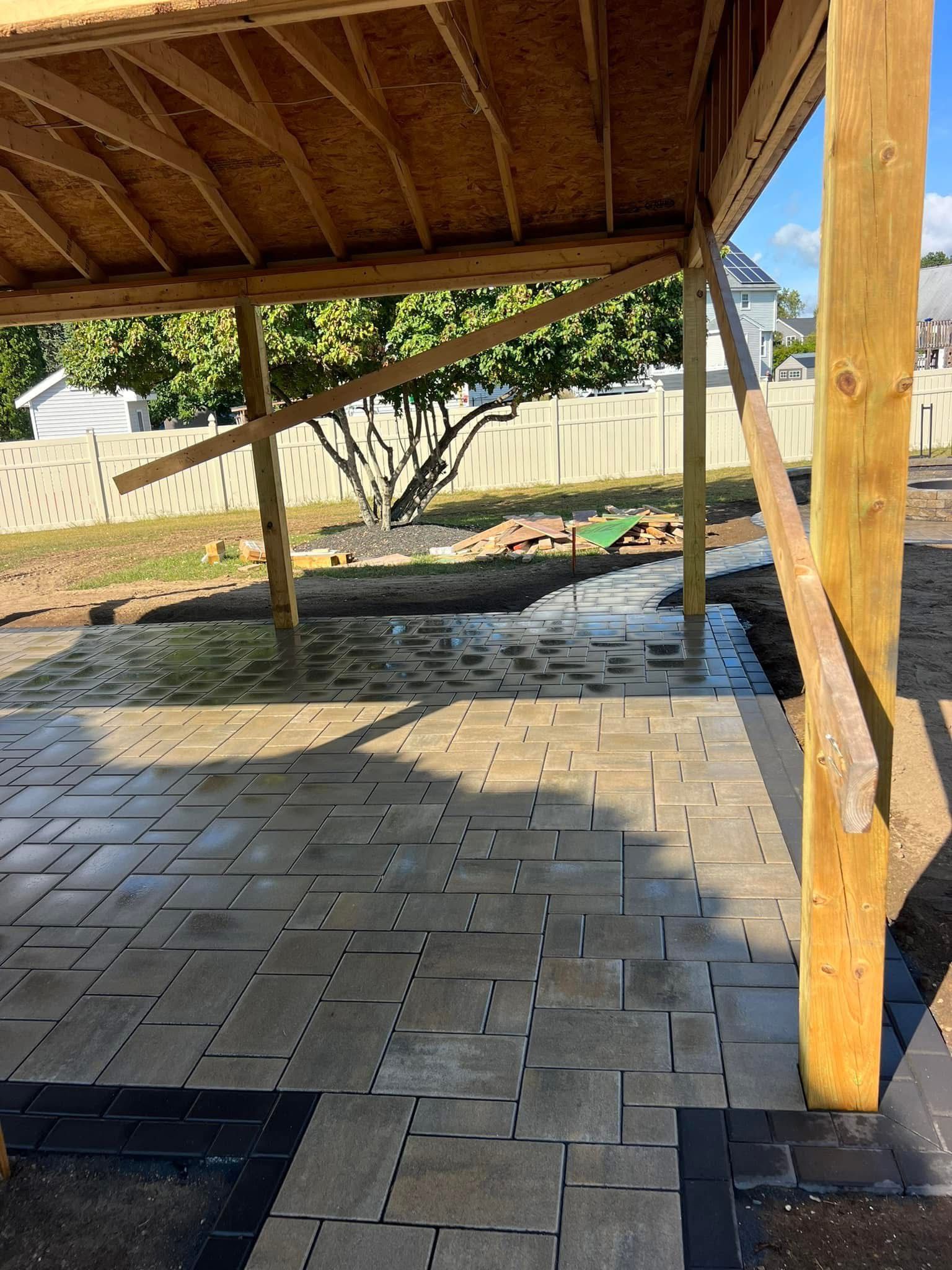 A patio is being built under a wooden structure.