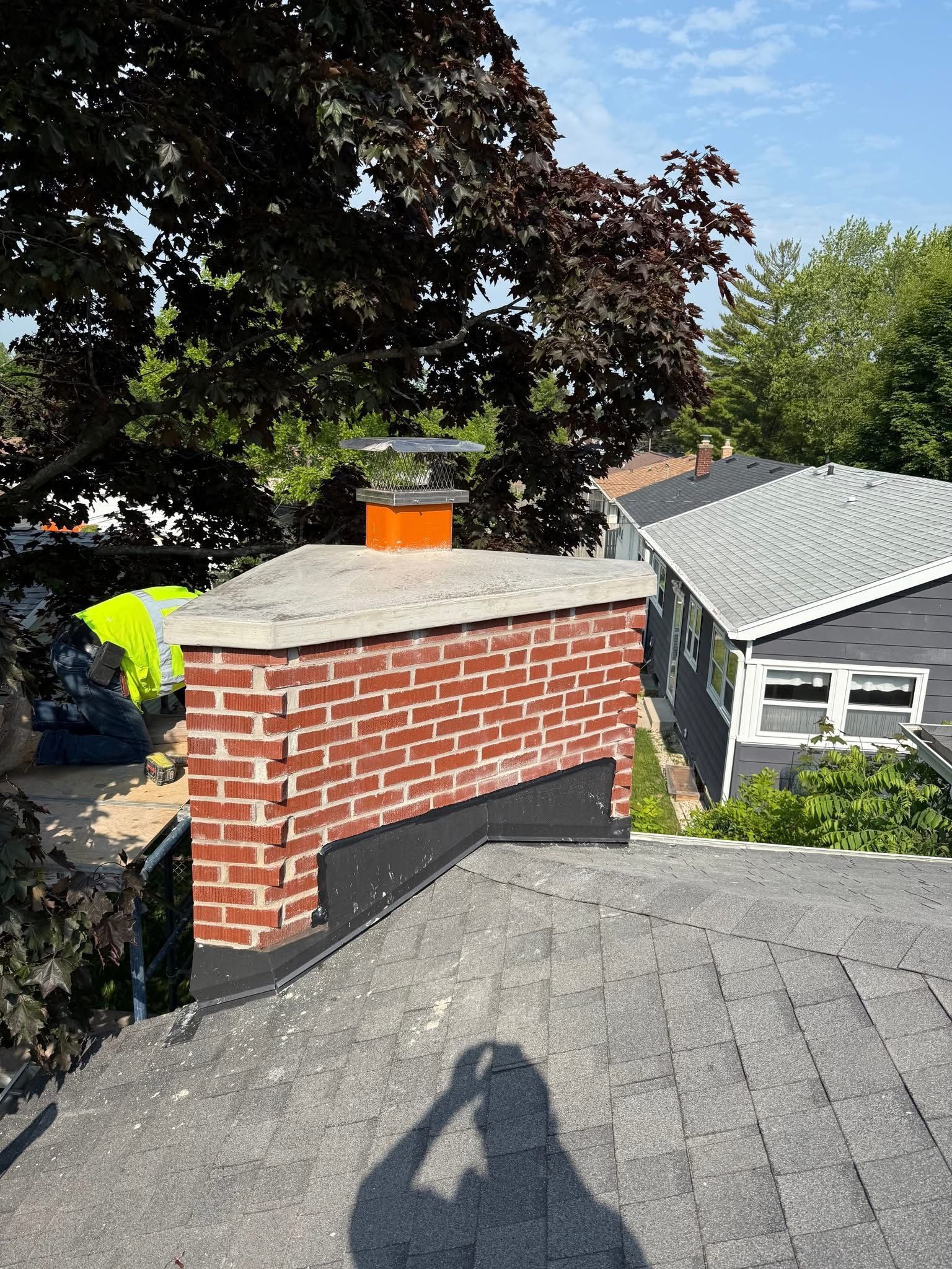 A brick chimney is on the roof of a house.